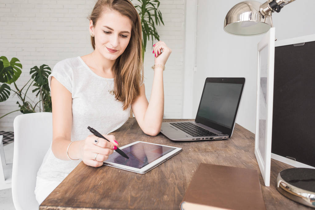 Молодая деловая женщина работает дома и рисует на планшете. Творческое рабочее пространство скандинавского стиля
 - Фото, изображение