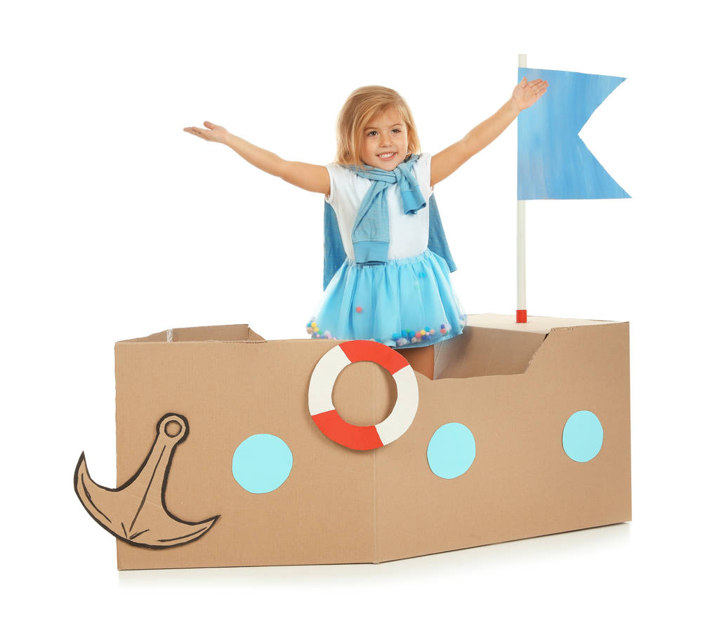 niedliches kleines Mädchen spielt mit Pappschiff auf weißem Hintergrund - Foto, Bild