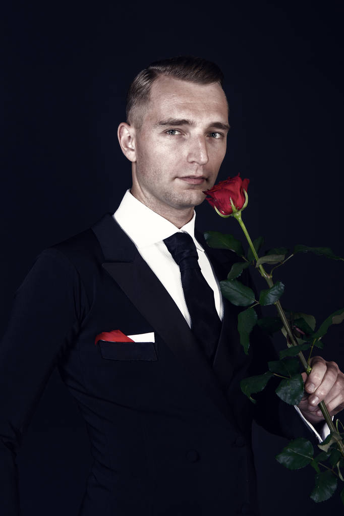 Siyah zemin üzerine kırmızı gül çiçek ile iş adamı - Fotoğraf, Görsel