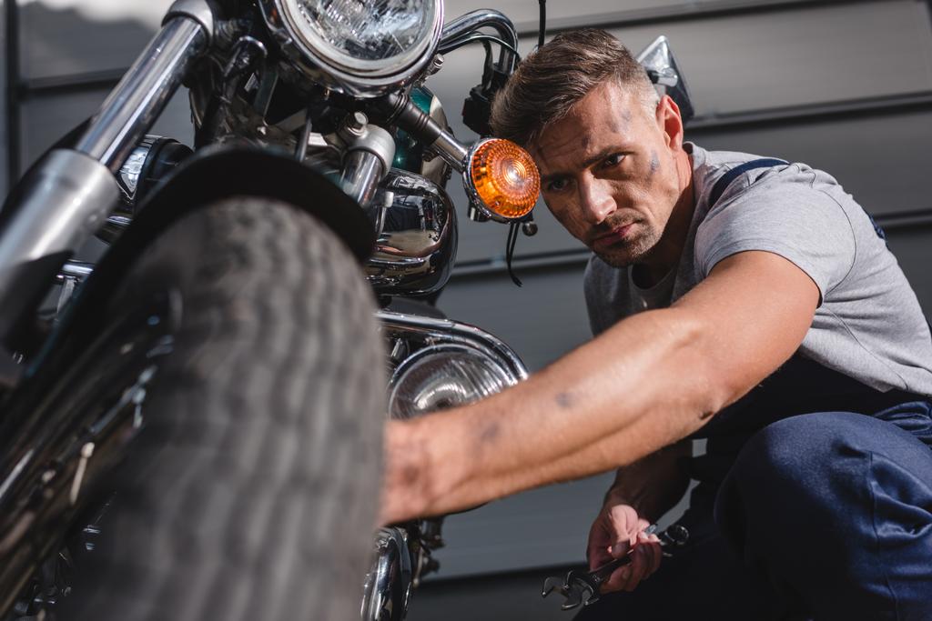 przystojny dorosłych mechanik Naprawa opon motocyklowych w garażu - Zdjęcie, obraz