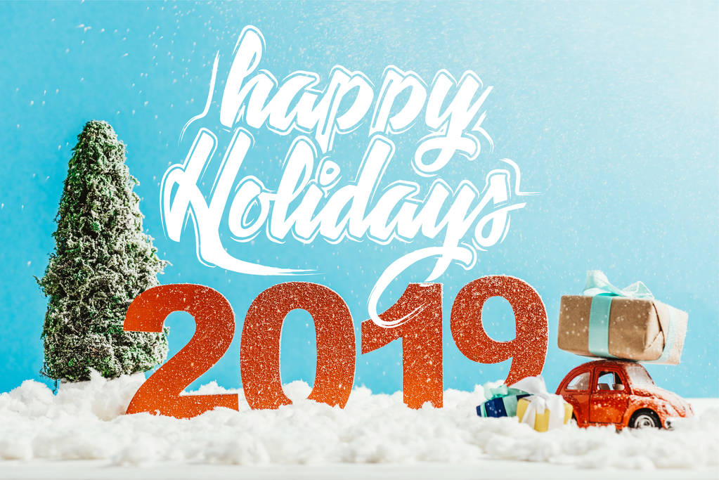 великі червоні номери 2019 року з іграшковим автомобілем, подарунками та ялинкою на снігу з написом "щасливі канікули"
 - Фото, зображення