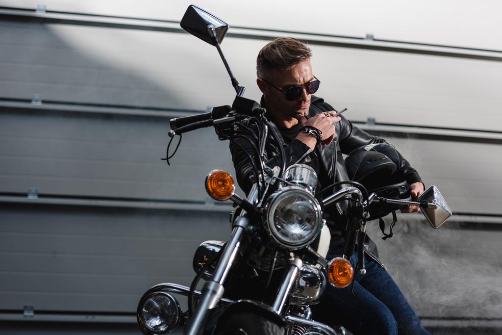rider clásico en gafas de sol negras sentado en moto en garaje
 - Foto, Imagen