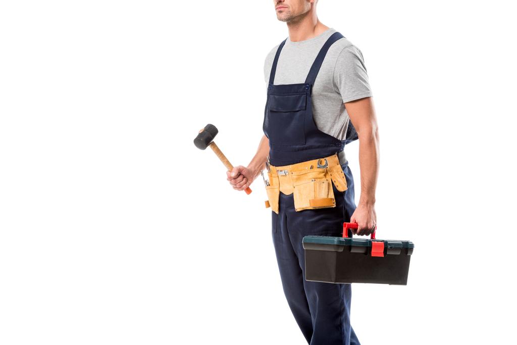 обрезанный вид строителя, держащего молоток и ящик с инструментами изолированные на белом
 - Фото, изображение