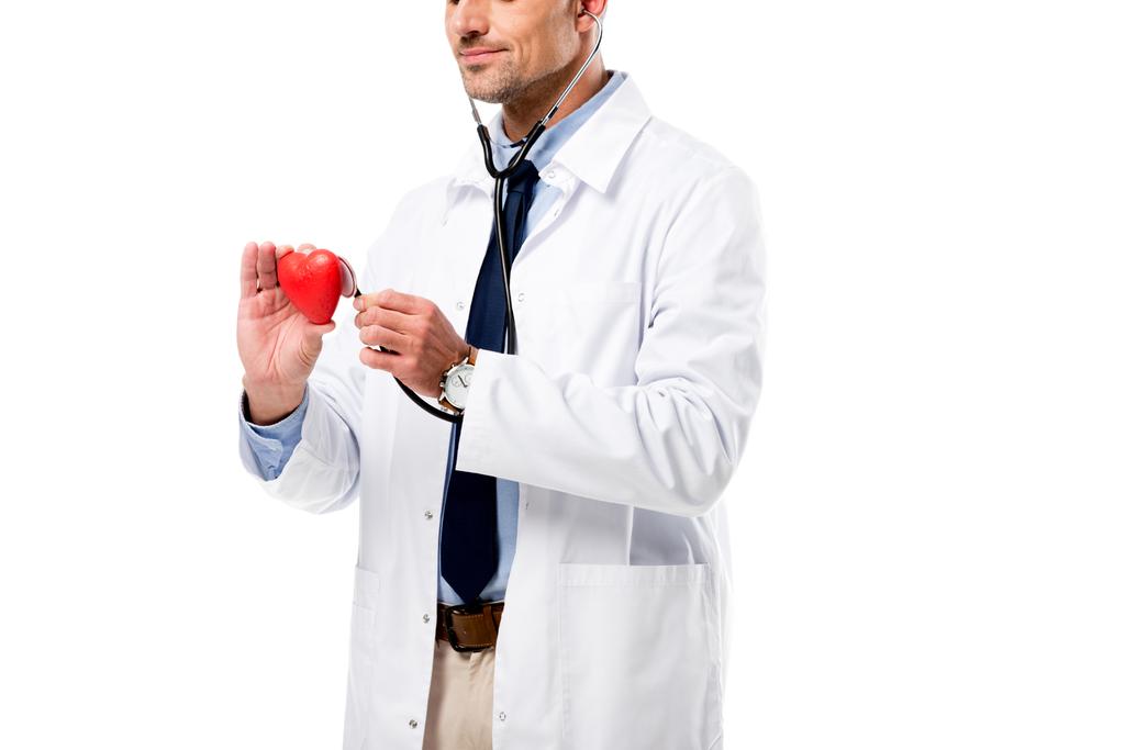 cropped view of doctor examining heart model with stethoscope isolated on white, heart healthcare concept - Photo, Image