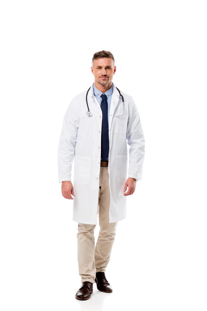 schöner Arzt in weißem Mantel mit Stethoskop, der isoliert auf weiß in die Kamera blickt - Foto, Bild