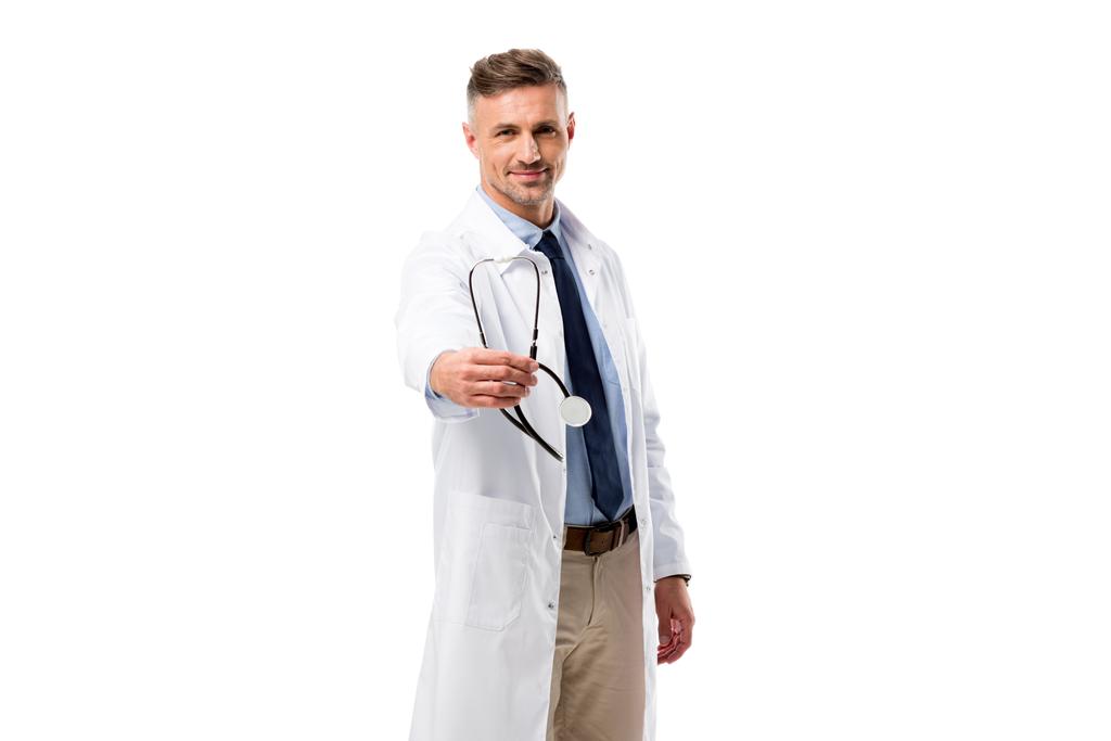 Przystojny lekarz patrzący w kamerę i trzymający stetoskop odizolowany na białym - Zdjęcie, obraz