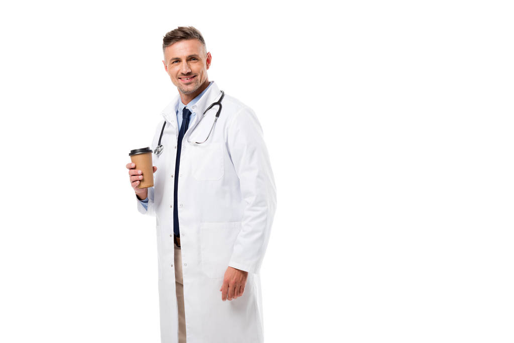 pohledný doktor při pohledu na fotoaparát a držení kávu sebou izolované na bílém - Fotografie, Obrázek