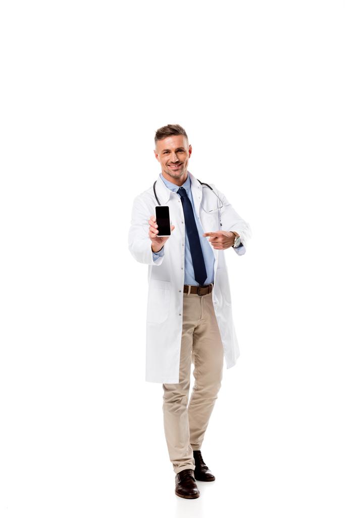 Médico sorridente apontando com o dedo para o smartphone com tela em branco isolada no branco
 - Foto, Imagem