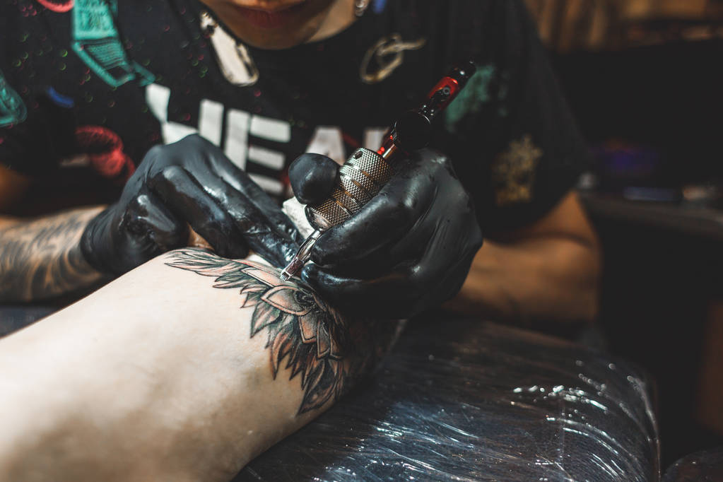 El artista del tatuaje crea una imagen en el cuerpo de un hombre. primer plano de las máquinas de tatuaje y las manos
 - Foto, imagen