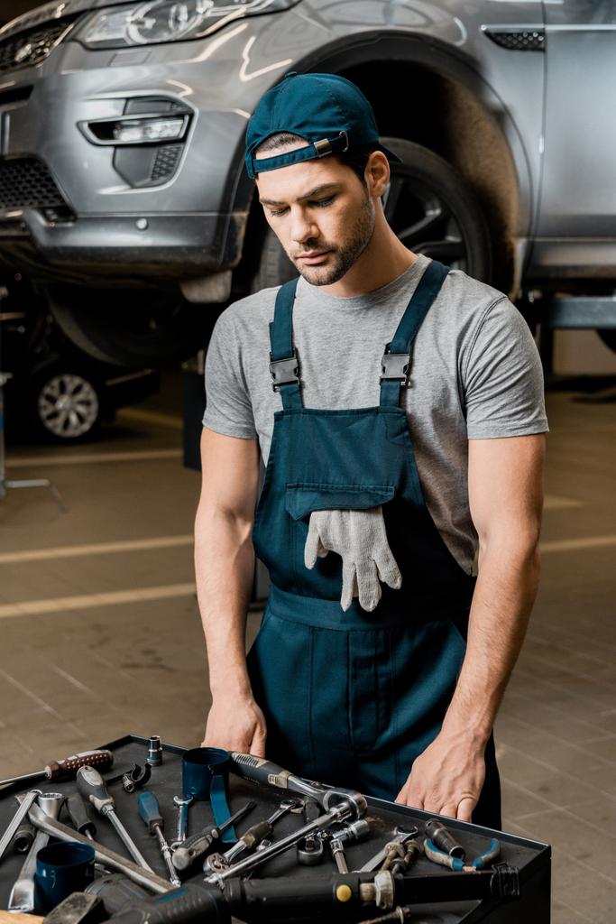 nuori korjaaja seisoo pöydällä mekaanikko työkaluja auto korjaamo
 - Valokuva, kuva
