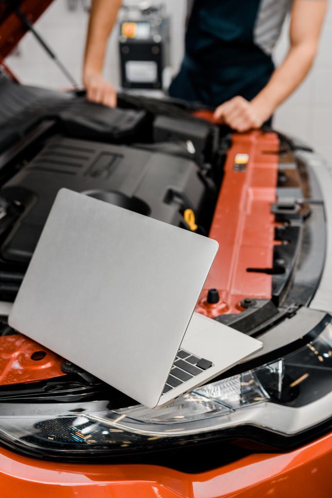 selective focus of laptop and auto mechanic at auto repair shop - Photo, Image