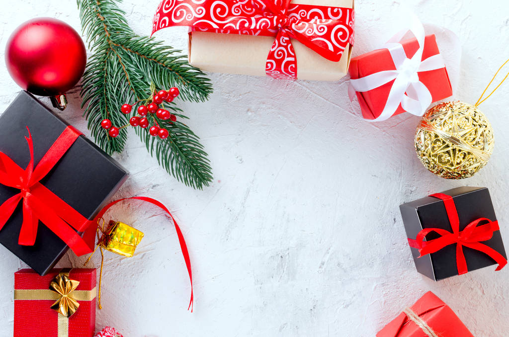 Weihnachten dekorativen Hintergrund mit Tannenzweigen, Zapfen, rote und schwarze Weihnachtsgeschenke, Kugel auf dem weißen Hintergrund. Kartenferienkonzept. Kopierraum, Ansicht von oben. - Foto, Bild