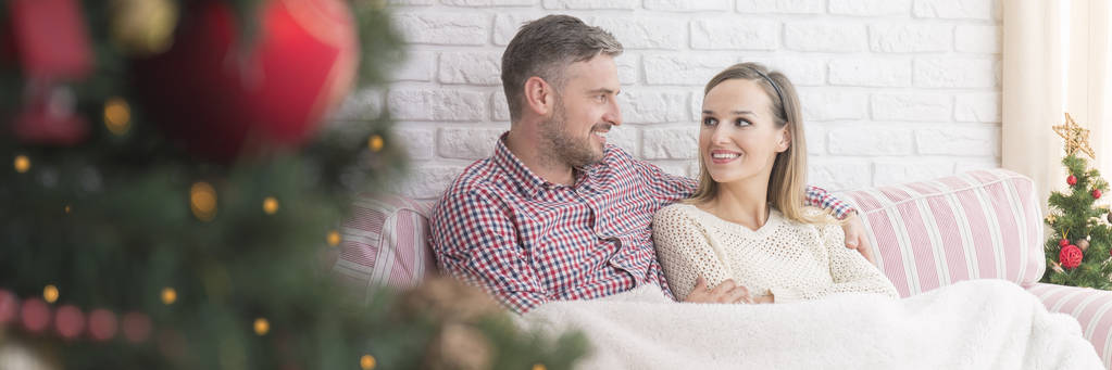 Weihnachtsmorgen mit glücklichem Paar, das zusammen sitzt - Foto, Bild