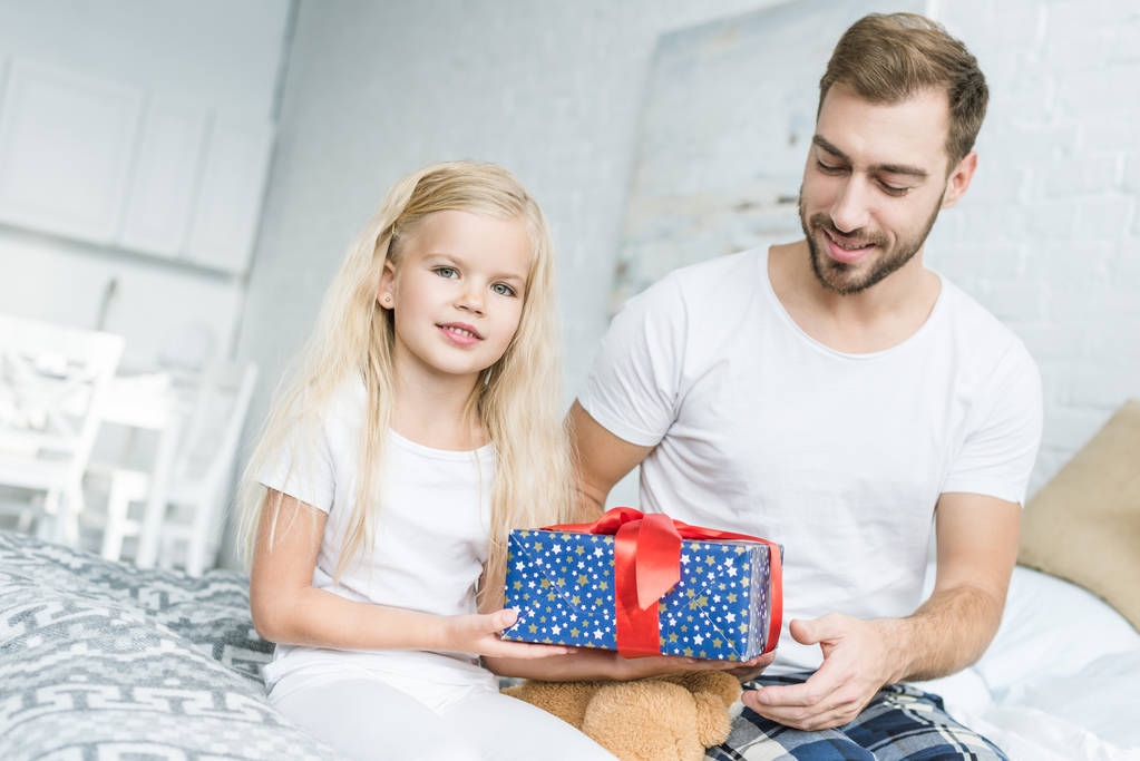 Boldog Apák nézett aranyos kis lánya gazdaság ajándék doboz otthon - Fotó, kép