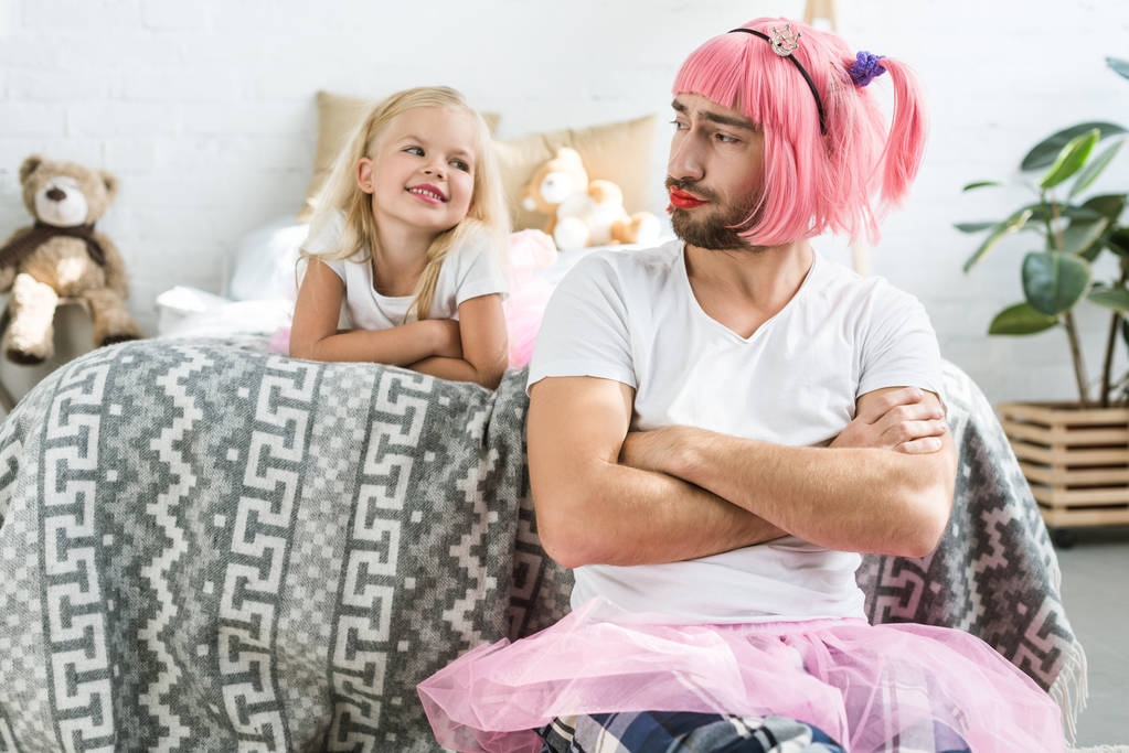 entzückend glückliche Tochter schaut Vater in rosa Perücke und Tutu-Rock an   - Foto, Bild