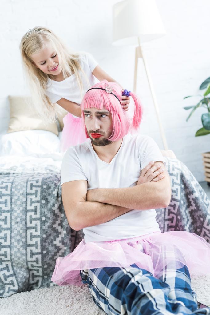 süße glückliche Tochter spielt mit Vater in rosa Perücke und Tutu-Rock  - Foto, Bild