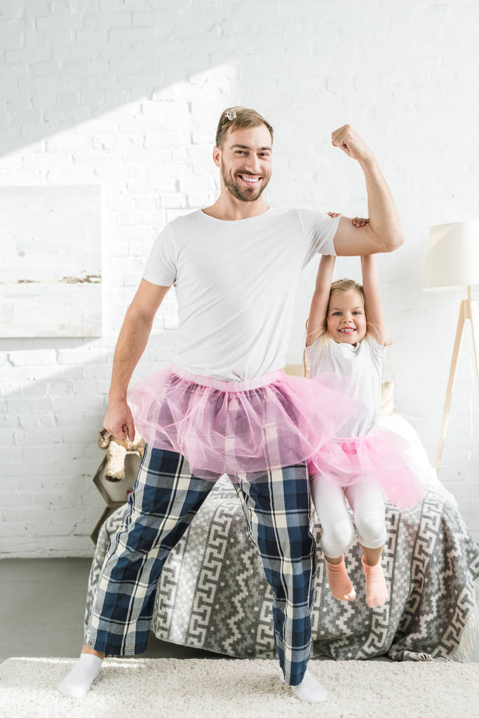 happy father and adorable little daughter in pink tutu skirts dancing and having fun at home - Photo, Image