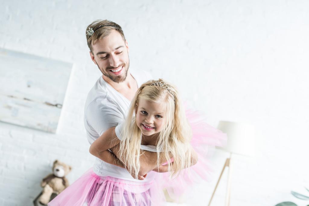 幸せな父と家で踊るピンクのチュチュ スカートの愛らしい小さな娘   - 写真・画像