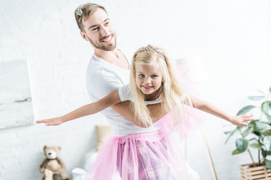 happy father and daughter in pink tutu skirts dancing at home  - Photo, Image