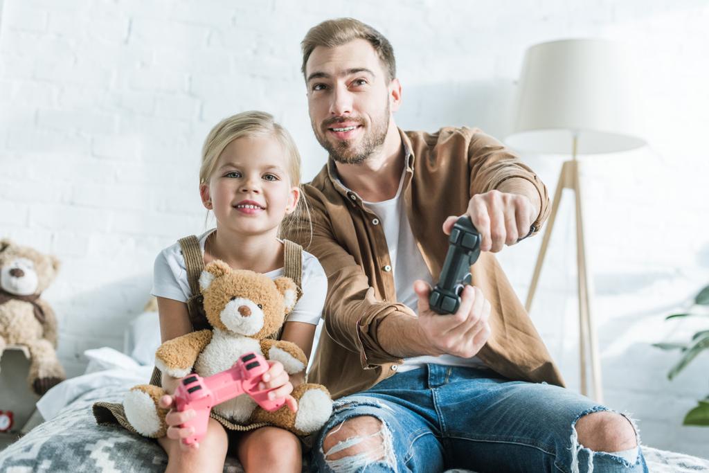 Vater und süße kleine Tochter spielen zu Hause mit Joysticks - Foto, Bild