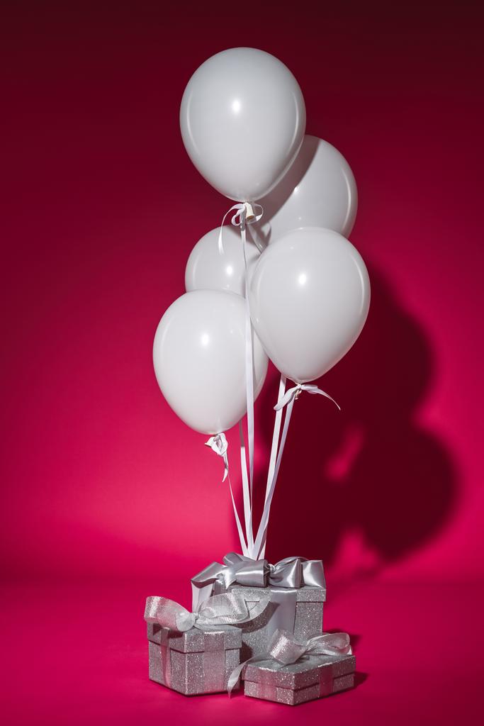 bundle of white balloons and silver gift boxes on burgundy - Photo, Image