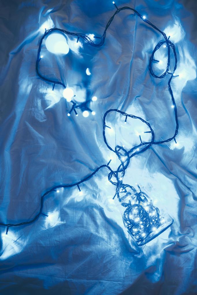 vista superior de las luces festivas de Navidad y tarro de vidrio en la cama
 - Foto, imagen