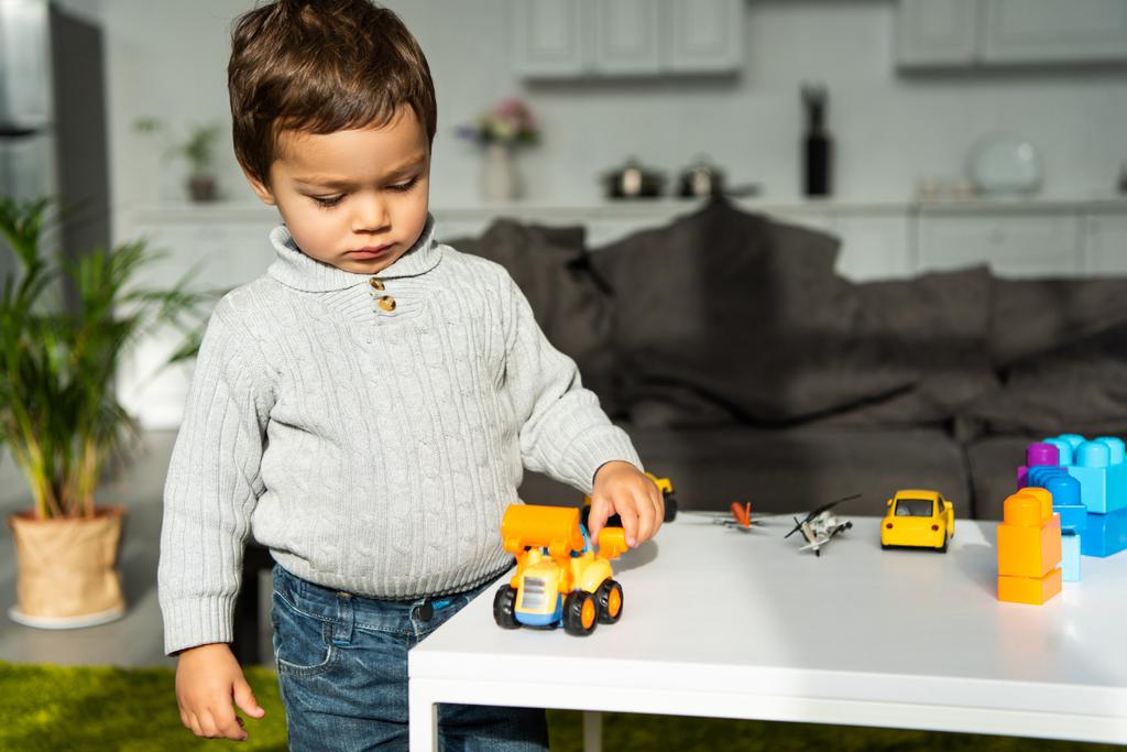 enfant jouant avec des voitures jouet à la table dans le salon à la maison
 - Photo, image
