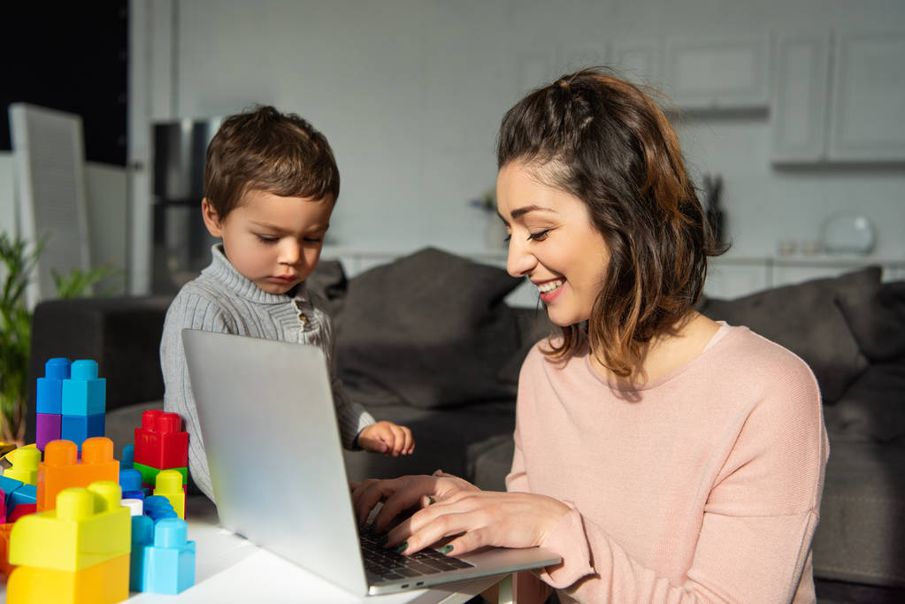 foco seletivo do menino e sua mãe usando laptop à mesa na sala de estar em casa
 - Foto, Imagem