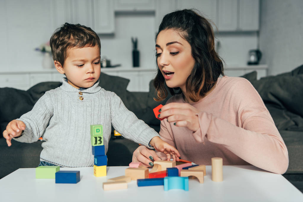 entzückende kleine Kind und seine Mutter spielen Blöcke Holz Turm Spiel zu Hause - Foto, Bild