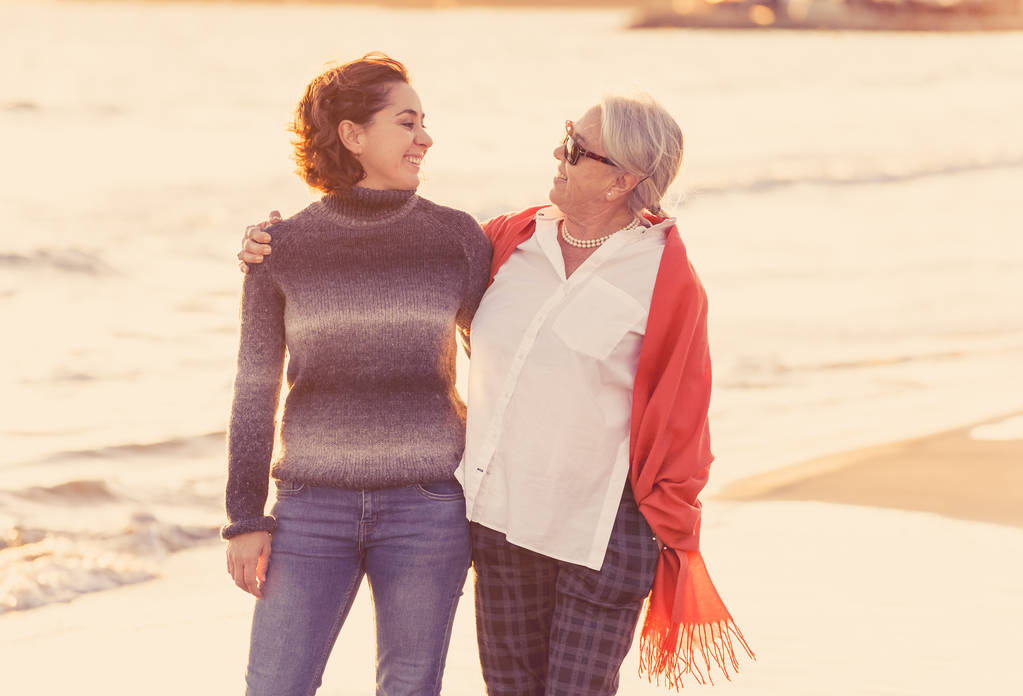 Портрет щасливої старшої матері і дорослої дочки, що проводить час разом, тримаючи руки сміючись і ходячи на пляжі на заході сонця світло в щасливі сімейні моменти Покоління пенсія і концепція людей
. - Фото, зображення