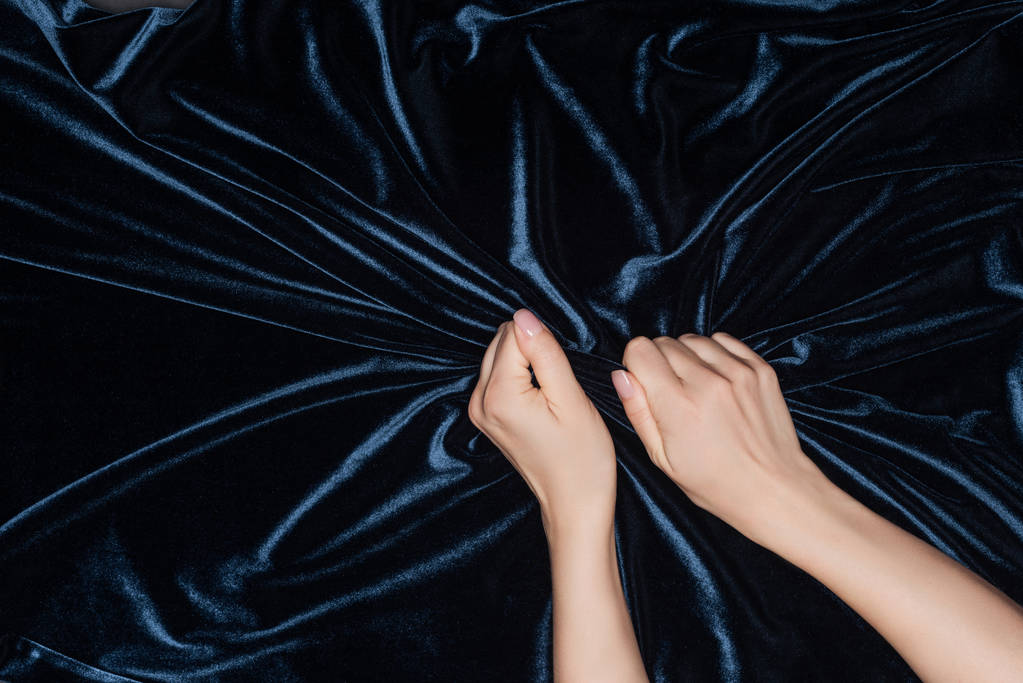 close up of female hands tightly holding black shiny velvet cloth - Photo, Image