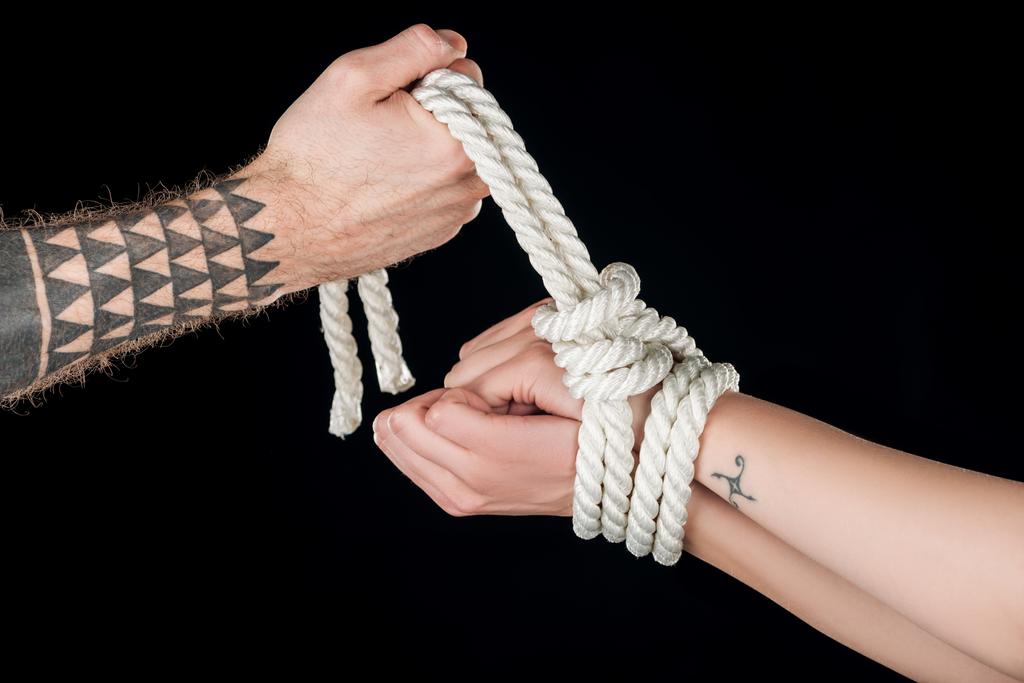 黒に分離・ タトゥーの女性の手でロープを結ぶ男の部分的なビュー - 写真・画像