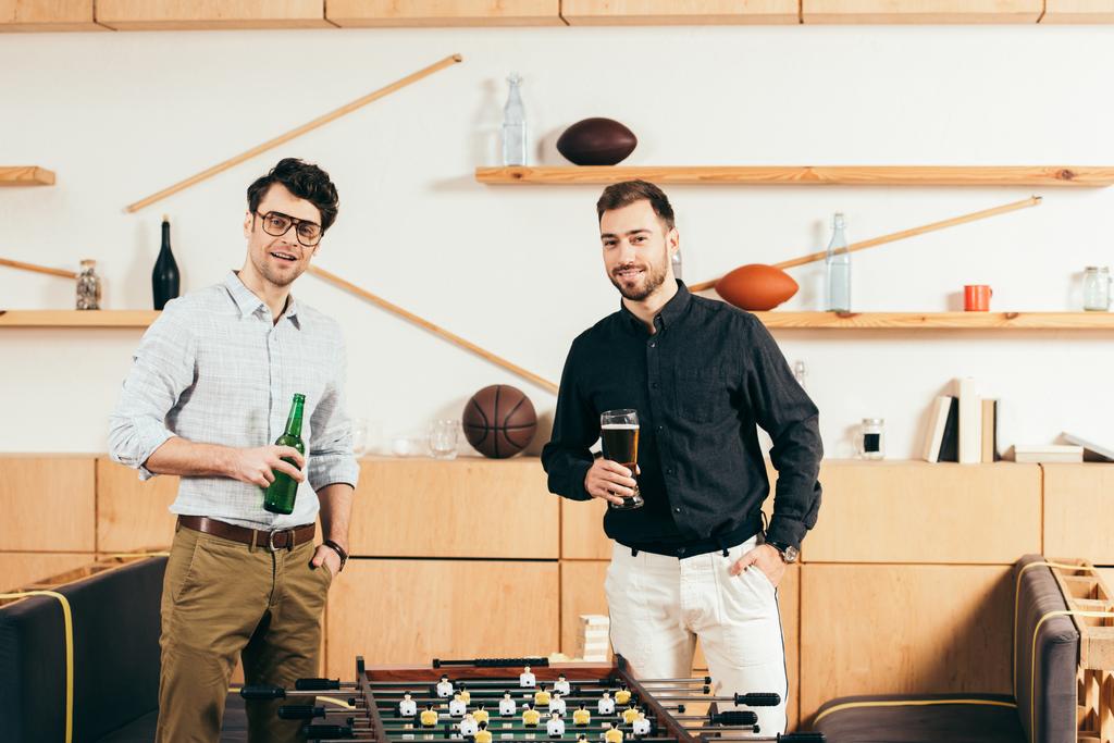πορτρέτο των νέων ανδρών με μπύρα στέκεται στο επιτραπέζιο ποδόσφαιρο στο καφενείο - Φωτογραφία, εικόνα