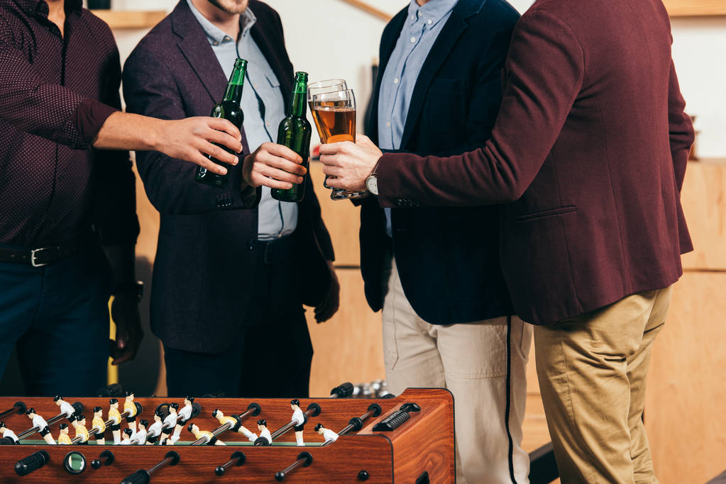 vista parziale di uomini d'affari clinking bevande a calcio balilla in caffè
 - Foto, immagini