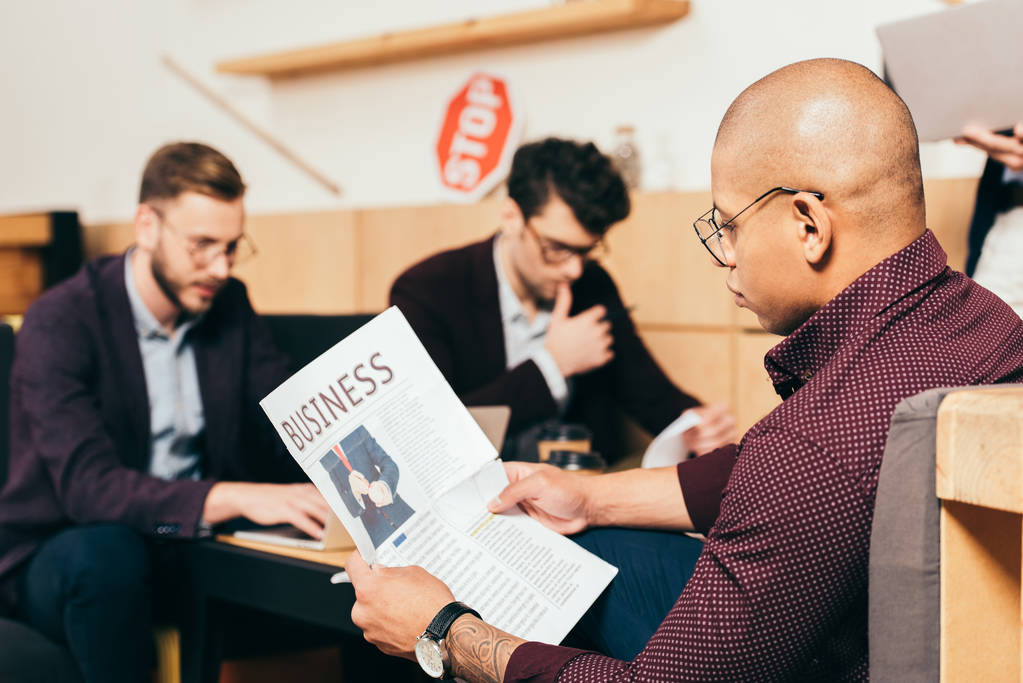 カフェで、近くの同僚と新聞を読んでアフリカ系アメリカ人のビジネスマン - 写真・画像