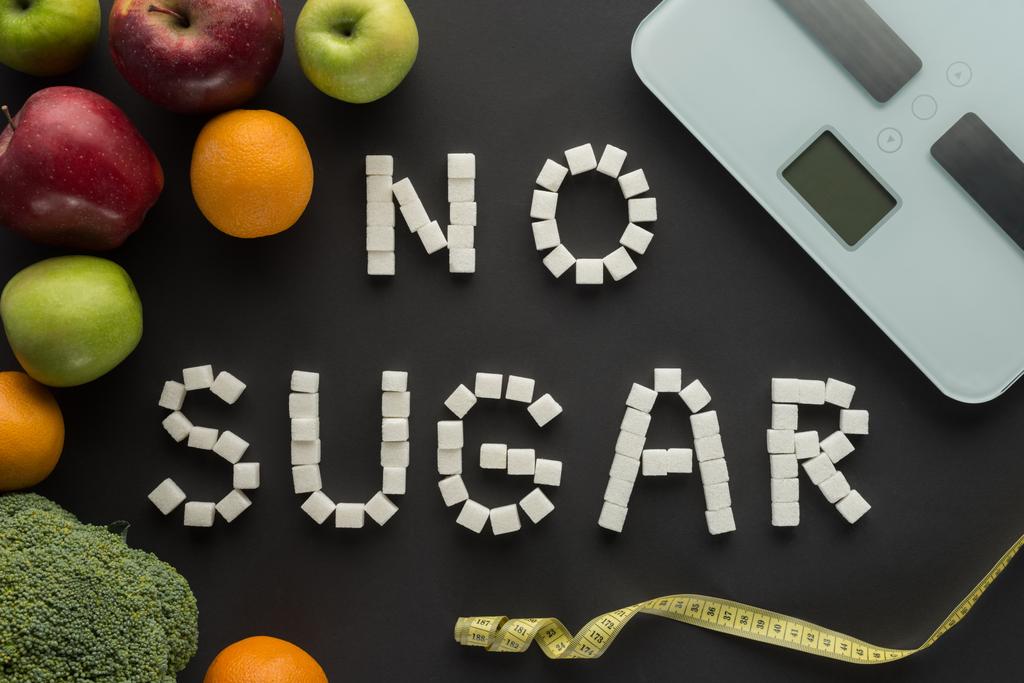 ylhäältä näkymä "ei sokeria" lause valmistettu kuutioista keskuudessa hedelmiä vaa 'at mustalla
  - Valokuva, kuva