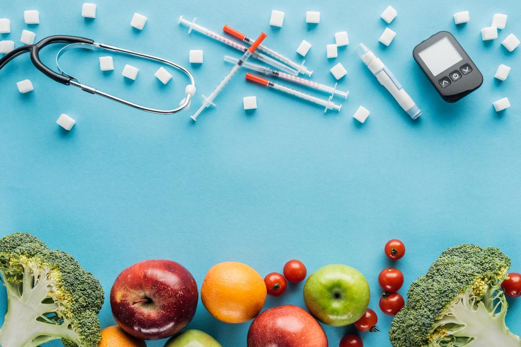 Medizinische Geräte, Zuckerwürfel und Früchte mit Kopierraum auf blauem Hintergrund - Foto, Bild