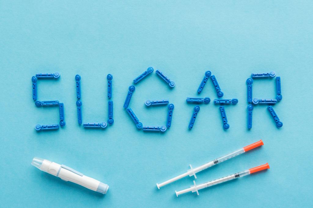 "ζάχαρη» λέξη με διαθέσιμου βελόνες και σύριγγες ινσουλίνης σε μπλε φόντο - Φωτογραφία, εικόνα