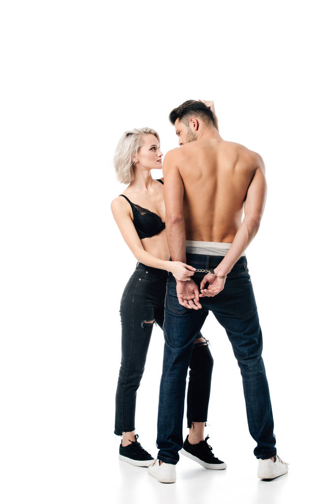красивая молодая женщина держит мужчину наручниками изолированы на белом
 - Фото, изображение