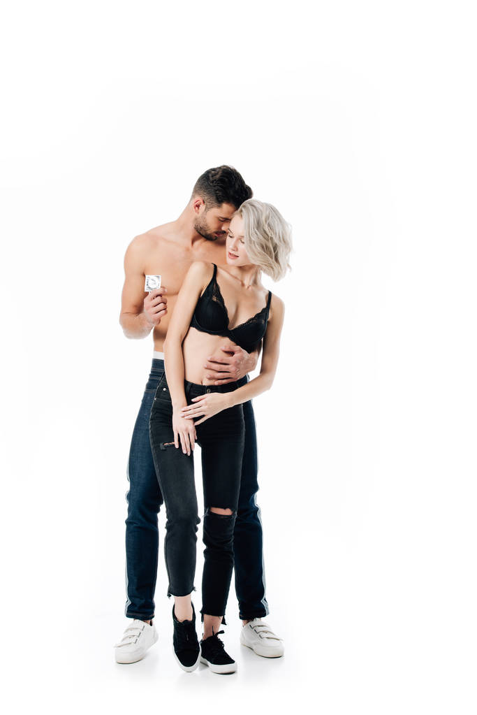 hombre abrazando a mujer y sosteniendo condón aislado en blanco, concepto de sexo seguro
 - Foto, Imagen