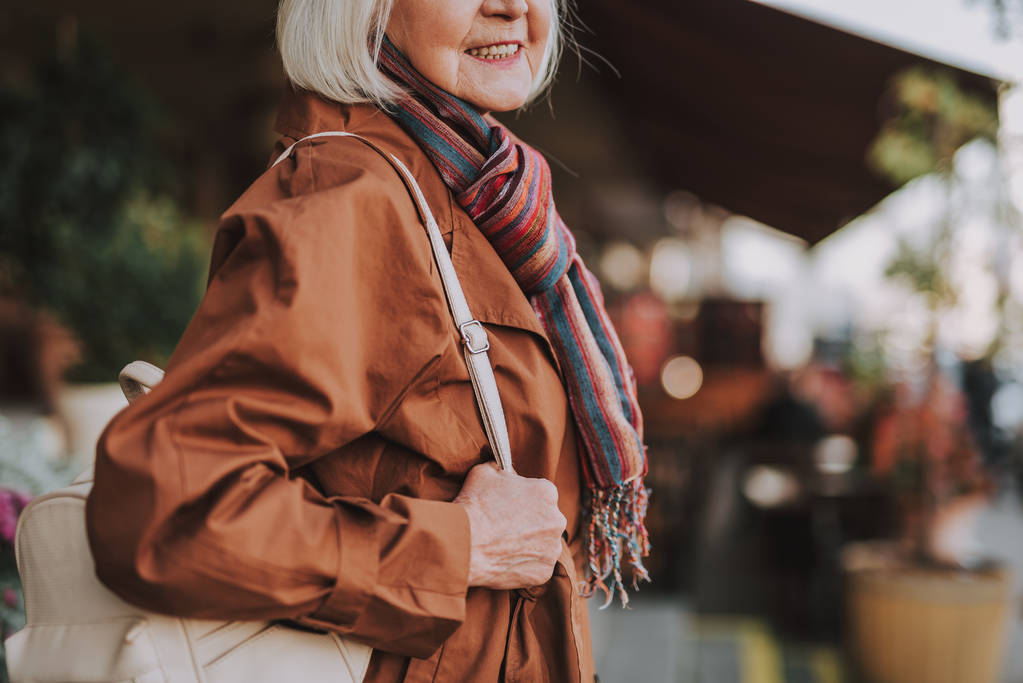 Стильная старушка с рюкзаком позирует на улице
 - Фото, изображение