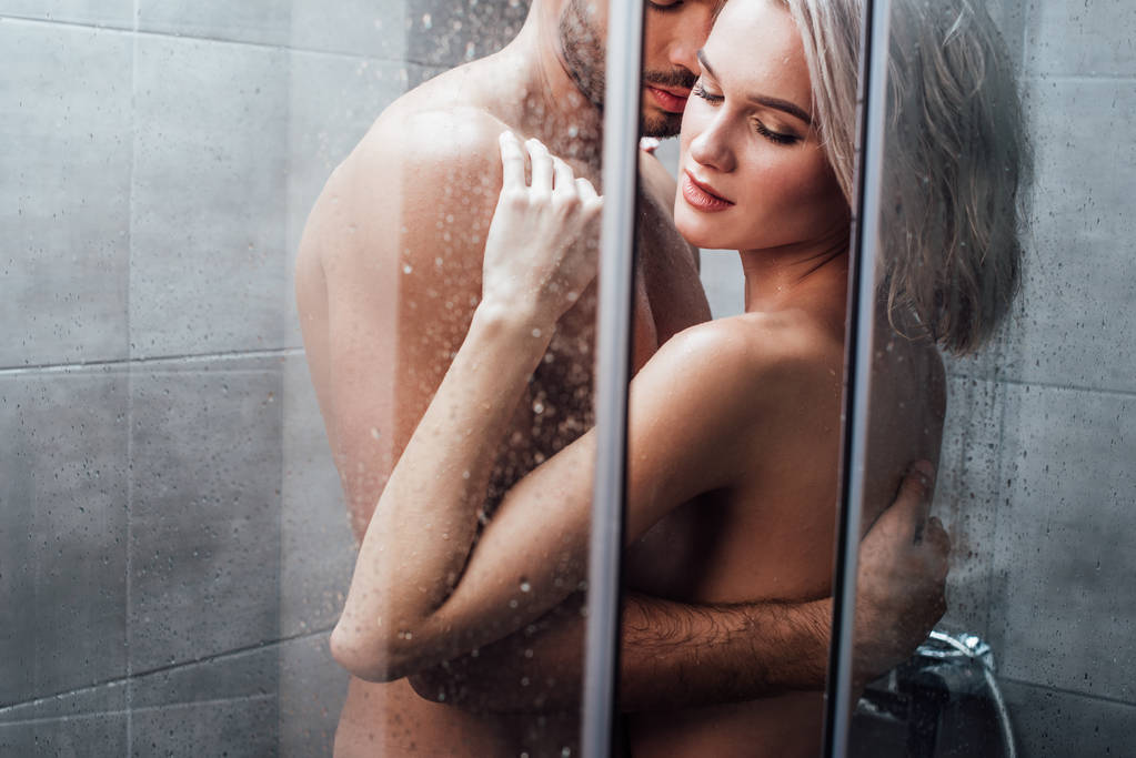 man passionately embracing attractive woman in shower  - Photo, Image