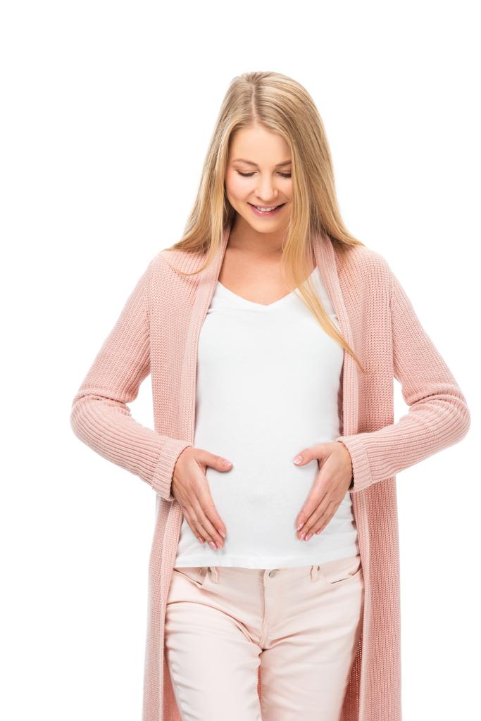glimlachend blonde zwangere buik met beide handen aan te raken en kijkt neer op geïsoleerde Wit - Foto, afbeelding