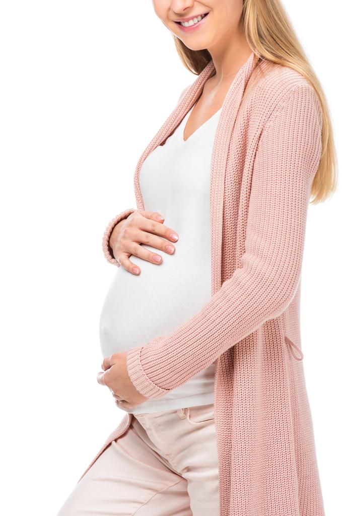 白で隔離の腹に触れるピンクのカーディガンで妊娠中の女性のトリミング ビュー - 写真・画像