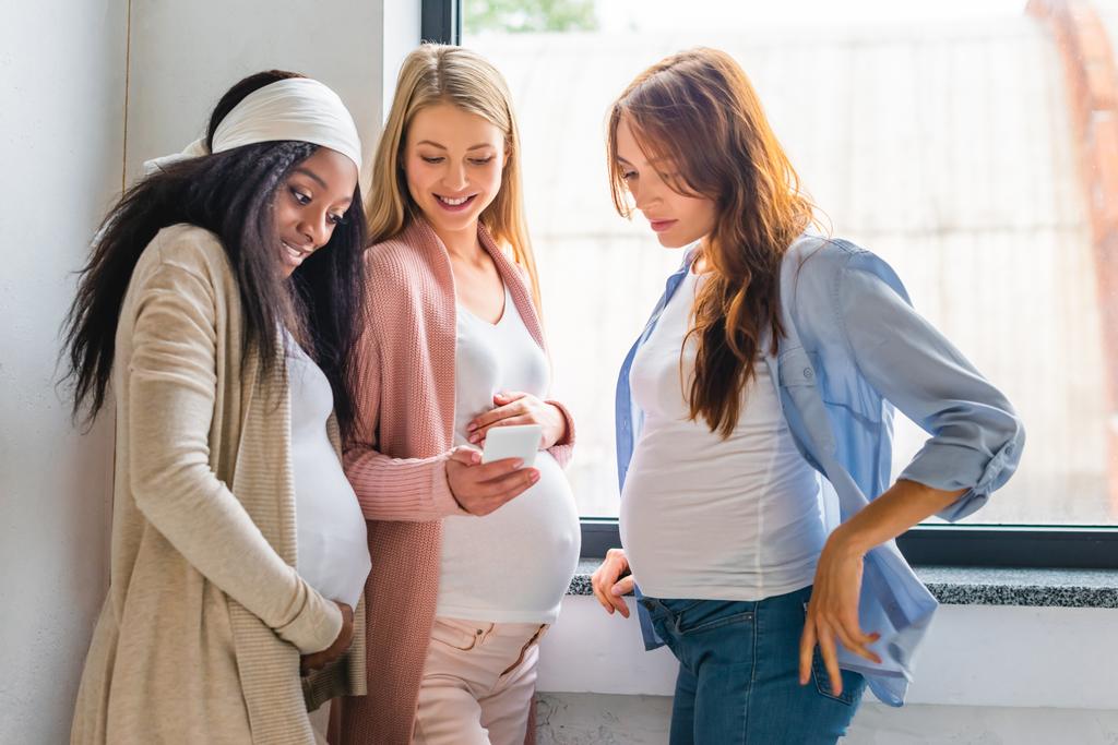 femmes enceintes joyeuses multiculturelles utilisant un smartphone
 - Photo, image