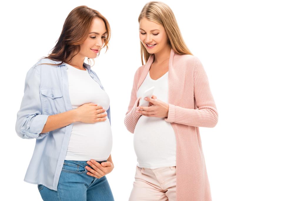 schöne lächelnde Schwangere mit Smartphone isoliert auf weiß - Foto, Bild