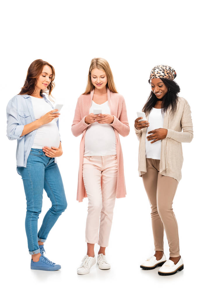 mulheres grávidas multiculturais sorridentes usando smartphones isolados em branco
 - Foto, Imagem