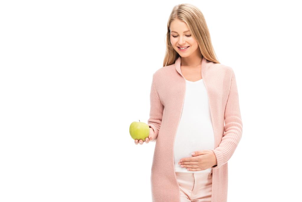hermosa mujer embarazada sosteniendo manzana verde y sonriendo aislado en blanco
 - Foto, imagen