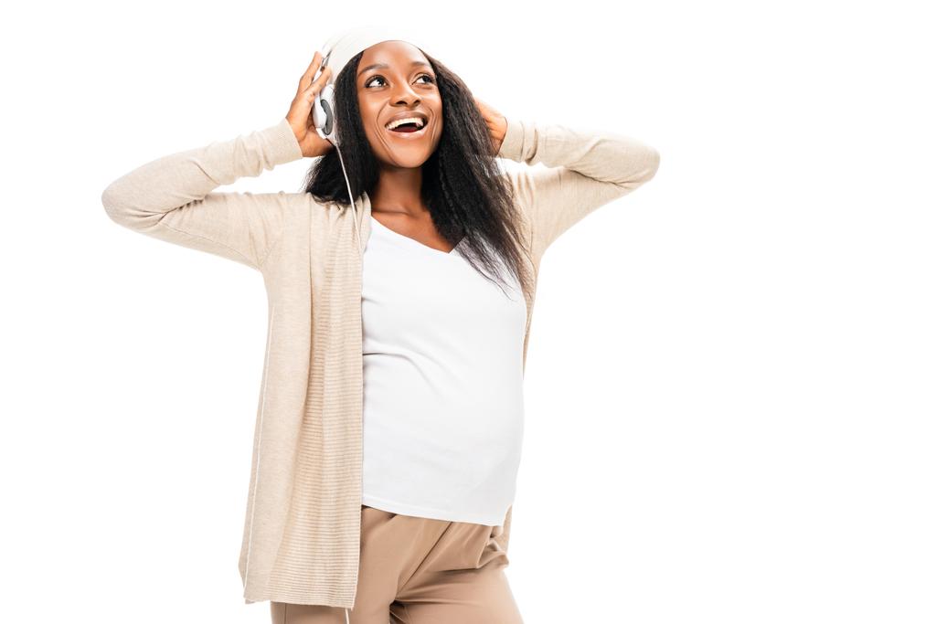 mujer embarazada afroamericana extática escuchando música en auriculares aislados en blanco
 - Foto, imagen
