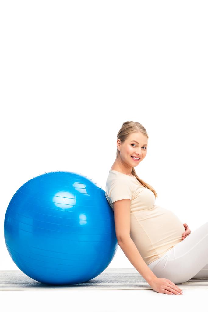 Kobieta w ciąży Blondynka, opierając się na fitness niebieski piłka na białym tle - Zdjęcie, obraz